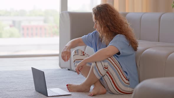 Lady with Curly Hair Using Computer in Living Room