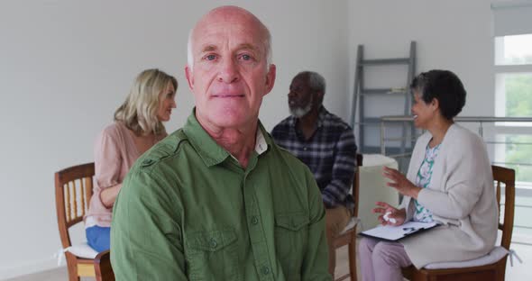 Two diverse senior couples sitting in circle having therapy conversation at home looking at camera alt