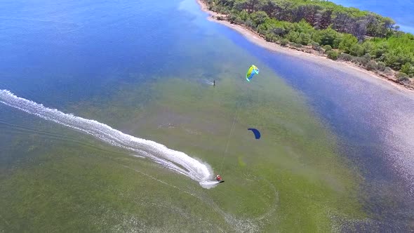 Aerial drone view of a man kiteboarding on a kite board. alt