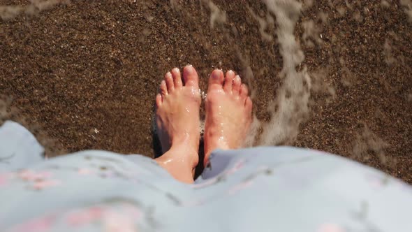 Female feet on sand near water.  alt