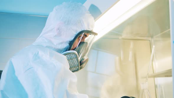 Male Scientist in a Hazmat Suit is Working with a Vacuum Cabinet alt