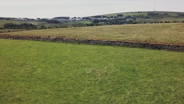 Drone ascending over a field in Dartmoor National Park in Devon England. Farmland with separating st alt