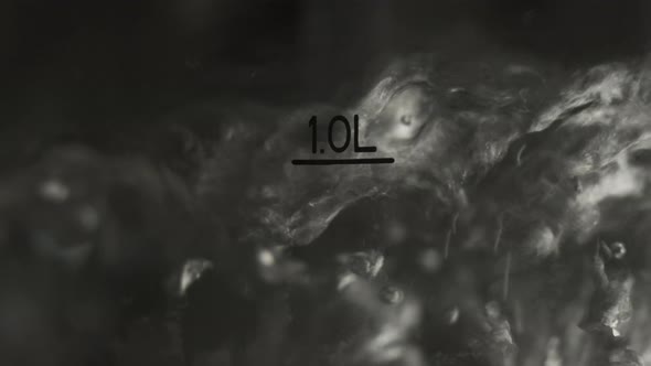 Close Up Footage of Water Boiling in Pot. We See Bubbles of Boiling Water with Mark 1 Liter alt