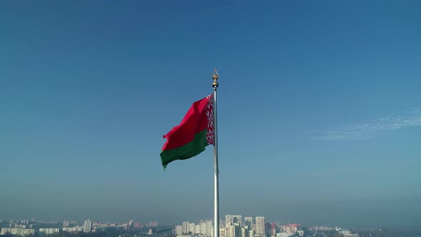 Belarusian Flag Waving Over Blue Sky and Minsk Cityscape on a Sunny Morning