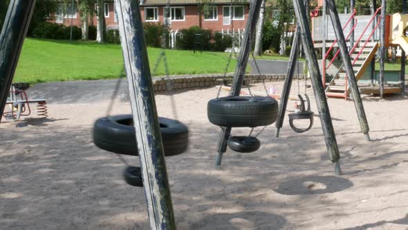 an Empty swing made up of used car tires swinging on a playground in the town of Partille outside of alt