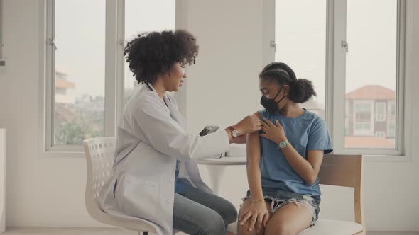 African american doctor is applying plaster to a child's shoulder after being vaccinated. alt