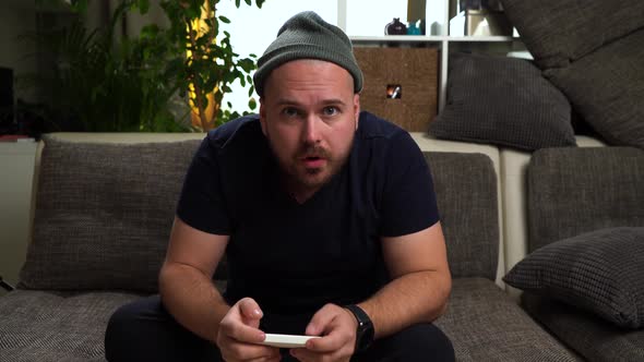 Young Attractive Guy Sitting on the Couch and Playing Console. Win the Game and Feel Happy. Man alt