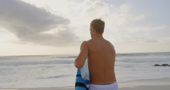 Man with surfboard on beach 4k