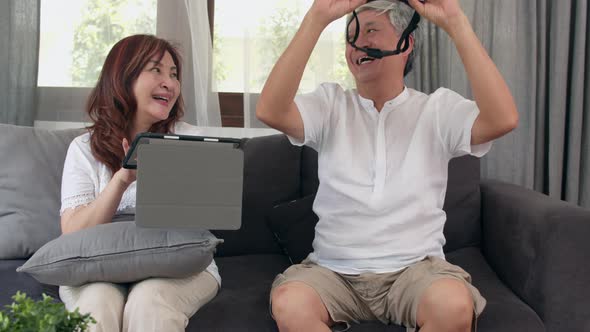 Asian elderly couple using tablet and virtual reality simulator playing games. alt