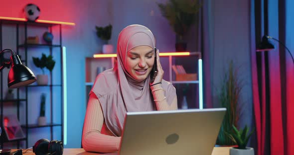 Arabic Woman Getting Good News on Laptop when Sitting at Her Workplace at Home alt
