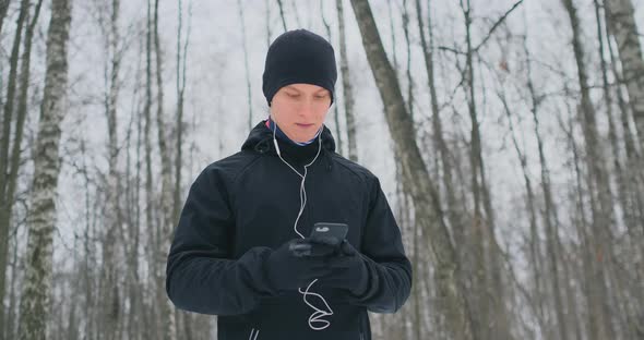 A Young Man in a Black Hammer in the Winter Is Preparing To Jog in the Park alt