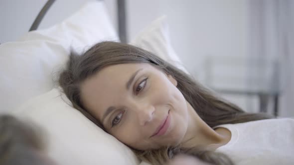 Smiling Woman Turning Aside to Her Husband in Bed