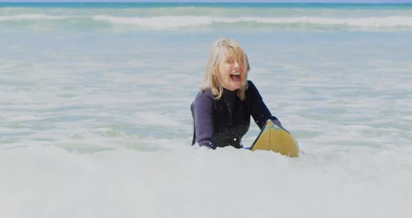 Front view of active senior Caucasian female surfer surfing on sea in the sunshine 4k alt