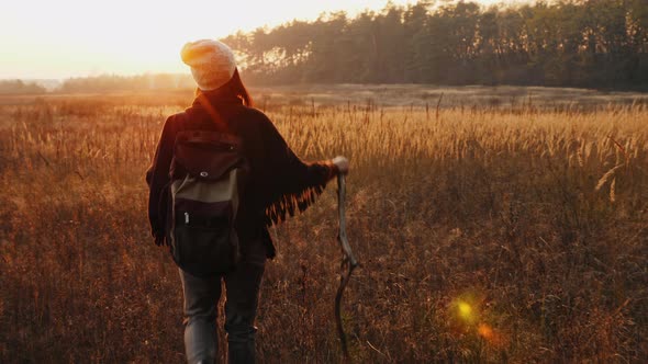 Female Hiker Walks Along Meadow Among Dry Grass alt