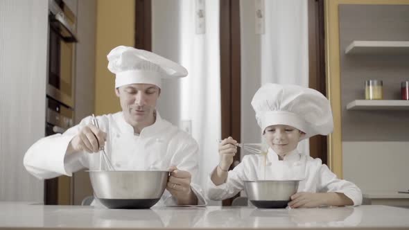 Dad and Son Mixing Food Ingredients in Steel Bowl in Their Home Kitchen