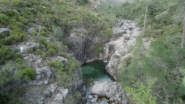 Aerial flying towards Portela do Homem Cascade, fresh water stream on Rocks, Tilt down