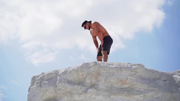 Shirtless athlete with strong body resting after heavy training on the sky background. alt