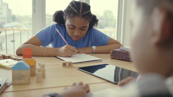 Child girl learning and writing homework in classroom. alt