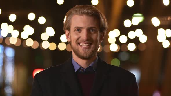 Young Confident Handsome Caucasian Male with Light Beard and Dark Coat Smiling at Camera Than alt