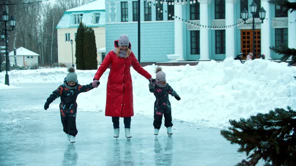 A Young Family of Mother and Two Children Skating on the Public Ice Rink alt