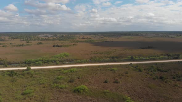 clouds moving across wetland swamp grass horizon vast road everglades florida aerial drone alt
