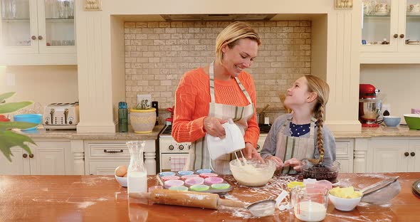 Smiling mother and daughter mixing mixture with electronic whisk 4K 4k alt