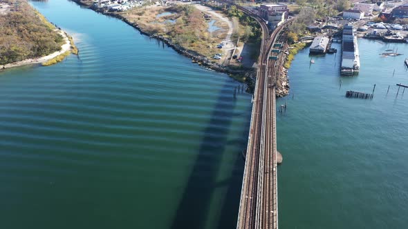 A high angle shot over elevated train tracks crossing a bay in Queens, NY. The camera dolly in direc alt