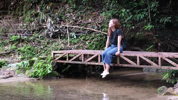 A young asian woman relaxing and sitting by the waterfall