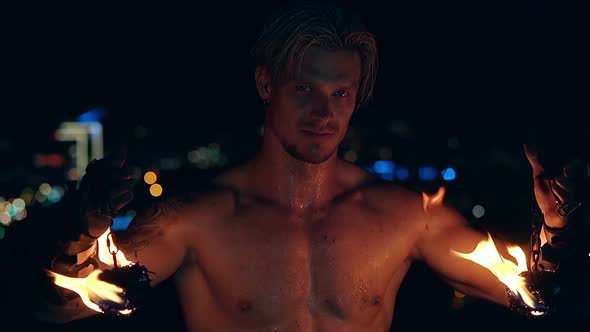 Young Blond Male Lowers Two Burning Pois Hanging on Chains. Slow Motion Shot. Close-up Shot. alt