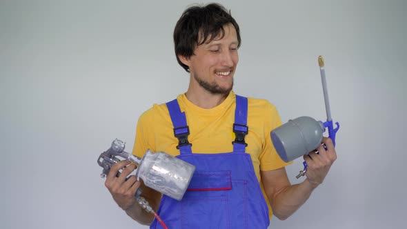 A Man Professional Home Renovator Holds Spray Painting Devices in His Arms alt