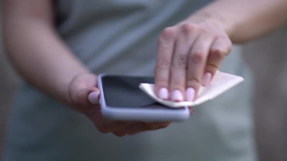 Woman Wiping Mobile Phone with a Napkin alt
