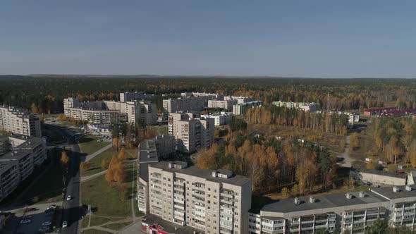 Aerial view of Russian city with panel multi-storey buildings. Around the forest. Autumn, sunny. 01 alt