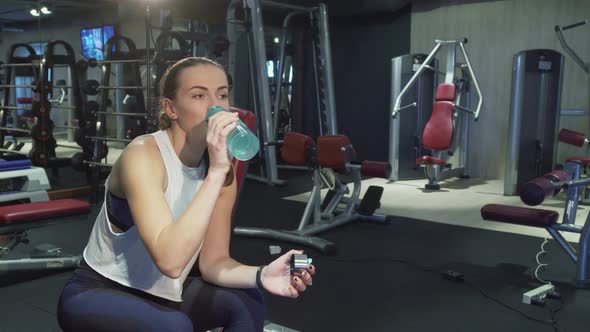 The Cute Girl Drinks Water in a Break Between Training Sessions