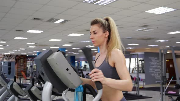 Young woman working out on orbi track at gym exercising alt