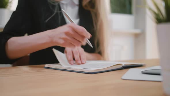Beautiful Young Blond Female Suit Sitting at Desk Writing with Pen in Notepad, Turning Page and alt