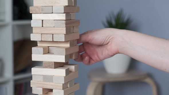 Woman is Playing in Board Game with Wooden Tower Together at Home