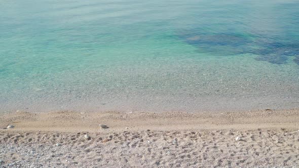 Video of the Coastline of the Sea and the Beach with a Calm Small Wave on a Summer Sunny Day alt