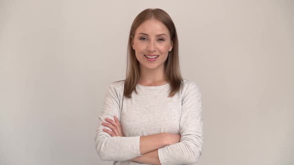 Portrait of happy woman standing with crossed hands and smiling. indoor studio shot alt