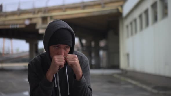 Front View Concentrated Sporty Man in Comfortable Clothes Boxing Practising on Street Under alt