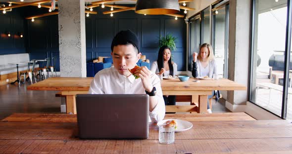 Businessman using laptop in cafeteria at office 4k