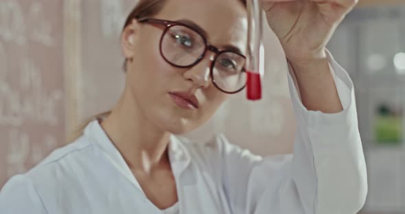 Young Female Chemist Doing Tests or Experiments in a Laboratory Checking a Chemical Mixture alt