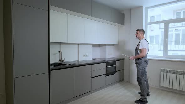 The Builder Checks the Quality of the Installation of Kitchen Furniture Construction alt