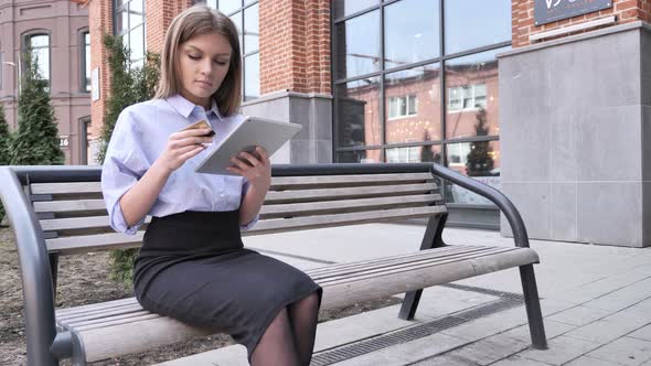 Online Shopping by Woman Sitting Outside Office Using Tablet alt