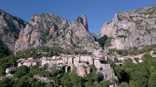 Huge limestone cliffs and Moustiers-Sainte-Marie village in France - aerial shot alt