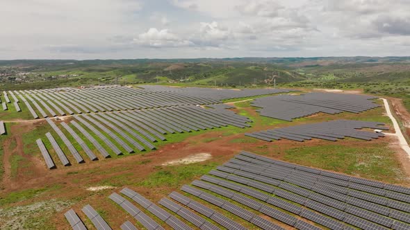 Long aerial shot of a solar farm with many rows of solar panels, in a hilly area in the Portuguese c alt