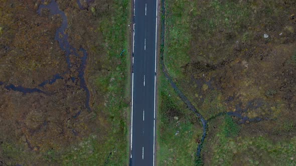 Aerial top down view of road on the countryside through an ample desolate val