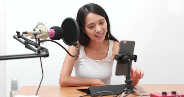 Beautiful woman having live stream on mobile phone at home  alt