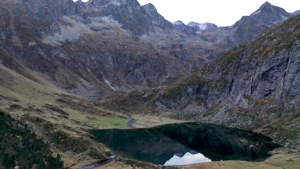 Lac d'Espingo mountain lake with calm water located in Haute-Garonne, Pyrénées, France, Aerial slow alt