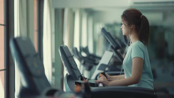Asian cute girl She was walking on the treadmill and listening to music at the gym, 4k resolution. alt