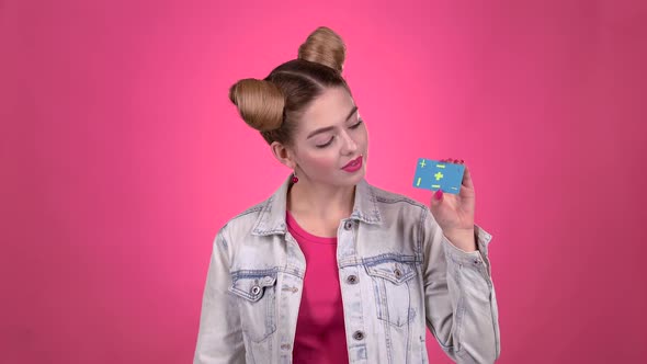 Teenager Advertises a Card and Shows a Thumbs Up. Pink Background. Slow Motion alt